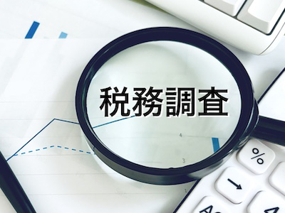 虫眼鏡で書類を確認する税務調査官